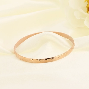 Rose gold teardrop bangle with hammered texture displayed on elegant beige silk fabric
