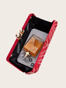Interior view of a red evening clutch with gold beads showing space for phone and perfume