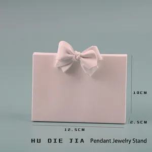 Pink resin pendant display stand with a bow detail on a soft blue background