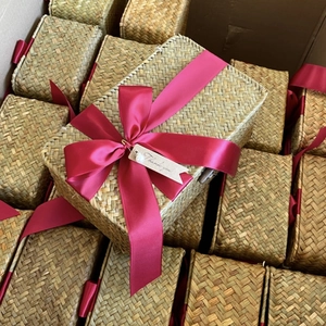 Detail of woven seagrass gift boxes with red satin ribbons and Thank You tags