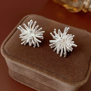 Macro view of silver flower stud earrings with sparkling zircons on a brown velvet box
