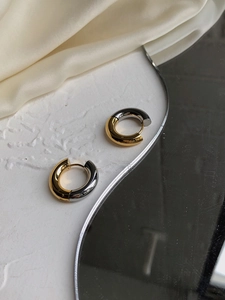 Macro detail of chunky two-tone gold and silver plated stainless steel hoop earrings