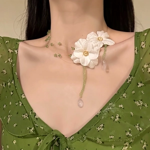 Close-up of fresh fabric flower necklace with green beads and pink water-drop pendant