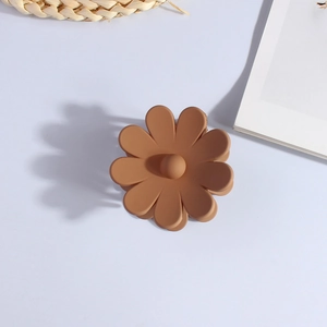 Detailed shot of a matte brown flower-shaped hair claw clip on a minimalist white background