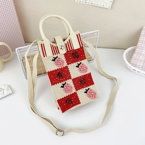 Detail of red strawberry knit crossbody bag with strawberry pattern and white handles