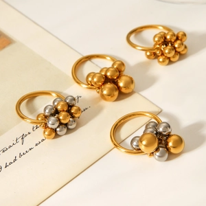 Détail de bagues à perles en acier inoxydable bicolore or et argent sur papier