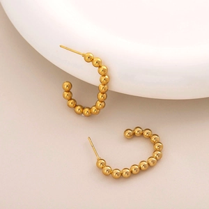 Detailed view of gold C-shaped earrings with polished bead texture and 18K plating
