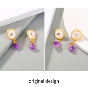 Detailed macro view of purple natural stone drop earrings with gold metal and shell inlay