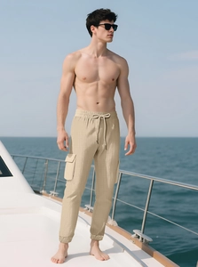 Detail of beige cargo pants with elastic drawstring waist and large side flap pockets
