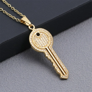 Detailed close-up of a gold-plated key pendant necklace set with sparkling micro-crystals