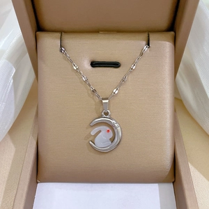 Detail of silver bunny necklace with moonstone inlay and red gem eye on champagne velvet