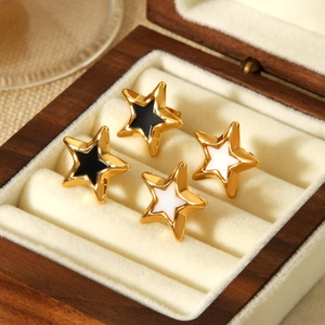 Detail view of gold-plated star stud earrings in black and white enamel on velvet lining