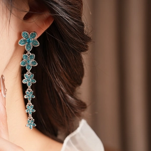 Gros plan de boucles d'oreilles vintage à fleurs avec cinq cristaux bleus et franges