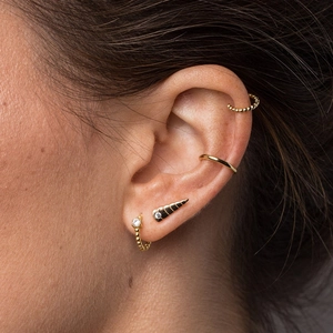 Close-up of gold-plated earring set with stud and cuff on a model's ear