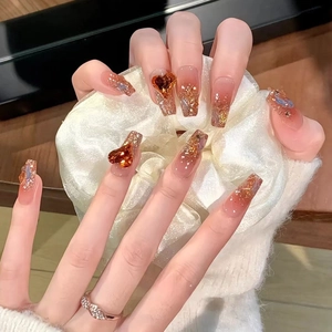 Amber gradient press-on nails with gold glitter flakes and 3D rhinestone hearts