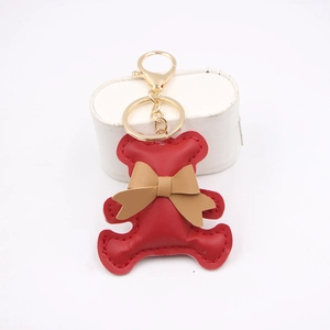 Close-up of a red leather bear keychain with brown bow and golden metal ring
