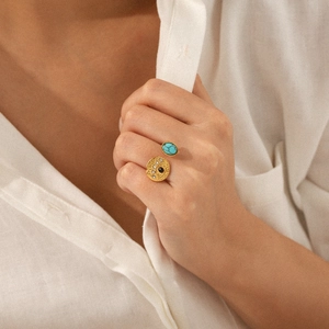 Detail eines Vintage-Goldrings mit Türkisstein und bösem Blick Motiv an einem Finger