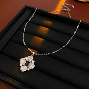Detail of silver necklace featuring a flower pendant with black zircon in a jewelry box