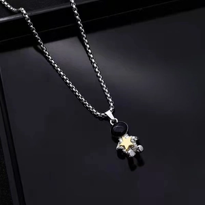 Macro shot of silver astronaut pendant holding a gold star on a box chain necklace
