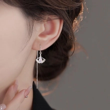 Close-up of silver long chain earrings with zircon fan charms on a female model