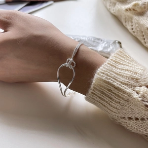 Minimalist S925 sterling silver knotted bracelet shown on model wrist with beige sweater
