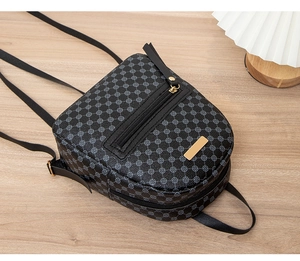 Close-up of black geometric pattern mini backpack with gold hardware on wooden background