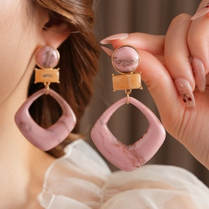 Detail of pink and beige marble textured resin geometric earrings worn by a model