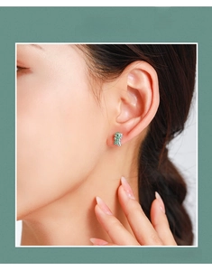 Détail d'une boucle d'oreille dinosaure en argent 925 avec zircons verts sur l'oreille