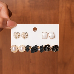 Detail view of five-pair stud earring set with pearls, enamel bows, and floral designs