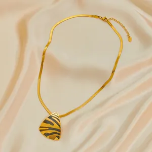Macro shot of gold snake chain with zebra print triangle pendant on silk