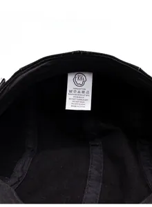 Detailed view of the 100% cotton care label inside the black cotton flat beret cap