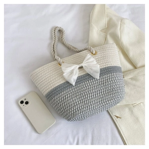 Detail of hand-woven cotton tote bag featuring large white bow and gray contrast design