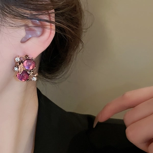 Close-up of rose gold floral earrings with pink purple gemstones on female model