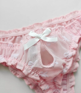 Detailed close-up of pink mesh lace thong with ruffle edges and white satin bow tie