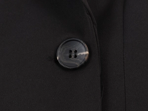 Close-up of black double-breasted blazer fabric texture and polished button detail