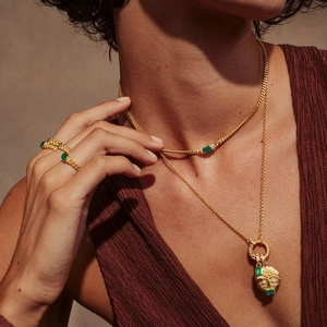 Vintage gold necklace and ring set with green gemstones featuring an artistic face pendant
