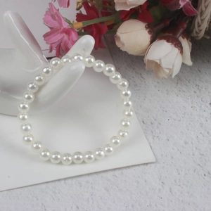 Detailed shot of a girls white pearl bracelet displayed on a ceramic hand stand