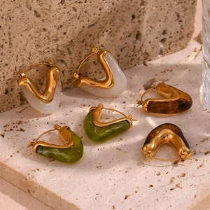 Detailed view of V-shaped acrylic hoop earrings in gold, white, green and amber colors