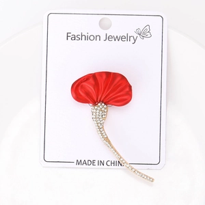 Detail of red fabric petal brooch with gold base and white rhinestones on display card