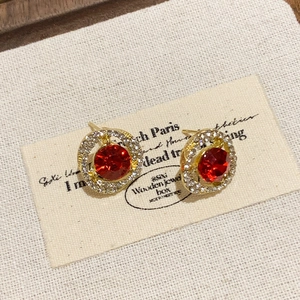 Primer plano de pendientes redondos vintage con piedra roja y halo de diamantes de imitación.
