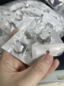 Detailed macro view of silver C-shape earrings with irregular lava foil texture in packaging