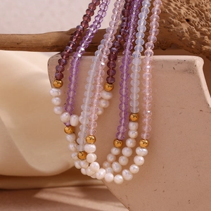 Artistic display of freshwater pearls and faceted colorful crystal beads on a wood branch
