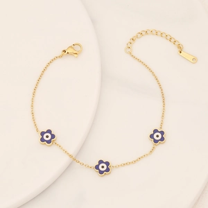 Detailed close-up of gold stainless steel flower bracelet with purple evil eye charms