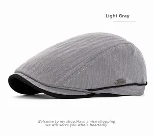 Macro shot of light gray herringbone fabric and metal logo detail on newsboy cap