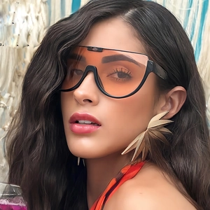 Fashionable orange semi-rimless sunglasses with gold feather earrings on a female model