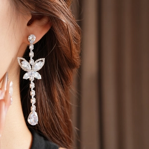 Macro detail of butterfly silver needle earrings with teardrop zircon crystals on model