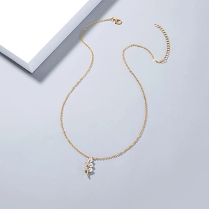Detailed close-up of golden leaf-shaped pendant with sparkling cubic zirconia on necklace