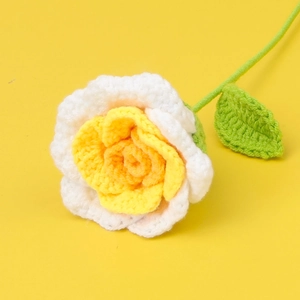Macro detail of handmade crochet rose with white petals and a yellow center on a yellow background