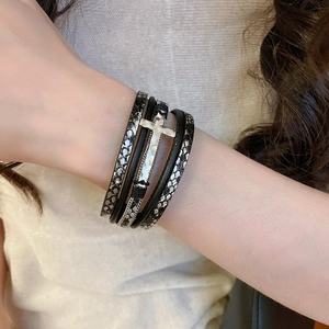 Gros plan détaillé d'un bracelet multicouche en cuir avec croix argentée et motif de serpent