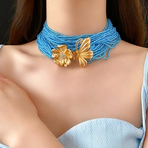 Detail of multilayer beaded necklace with blue beads and golden butterfly accents